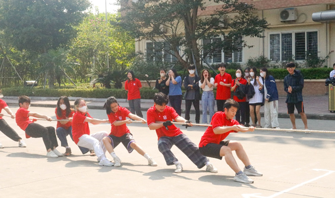 A group of people in red shirts pulling a rope

Description automatically generated